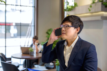 Young men are using mobile phones in modern workplaces..