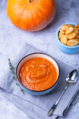 Pumpkin cream soup with croutons and thyme in a bowl. Vegetarian homemade soup. Gray background, close-up.