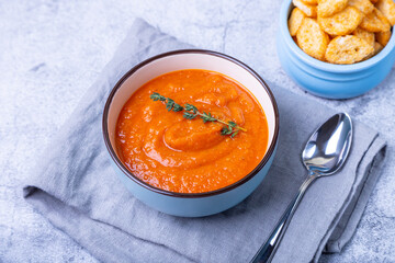 Pumpkin cream soup with croutons and thyme in a bowl. Vegetarian homemade soup. Gray background, close-up.