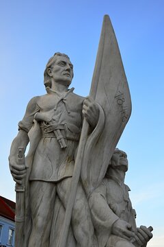 Statue of two Slovak volunteer soldiers from Slovak Uprising of 1848/1849, first holding flag and rifle, with percussion pistol behind his belt. Blue skies in background