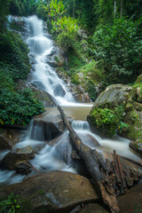 Waterfall landscape. Beautiful hidden waterfall in tropical rainforest. Foreground with big stones. Slow shutter speed, motion photography. Travel and adventure.