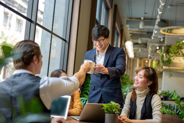 Naklejka premium Asian business group Is agreeing to hit coffee cup work in a coffee shop and smiling.