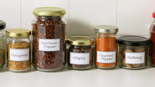 Recycled glass jars with a variety of dried herbs in a row
