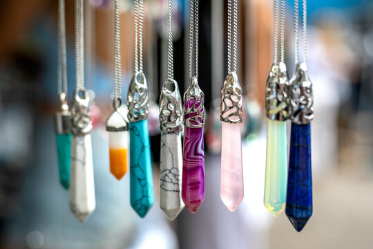 Multi colored gemstones and crystal pendants blurred background