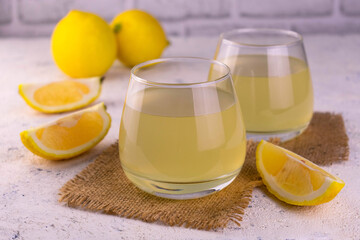 
Two glasses of freshly squeezed lemon juice on a white background.