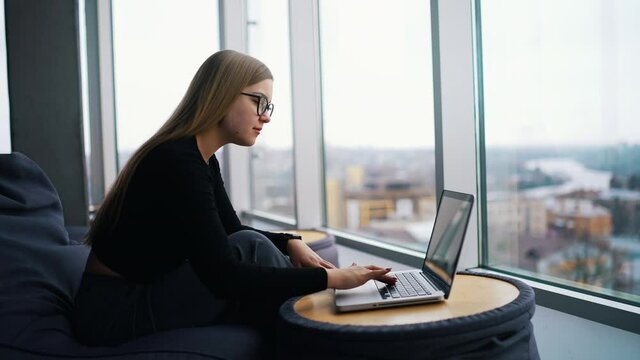 Young beautiful woman with glasses working on laptop.