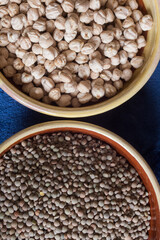 Overhead view of two clay bowls on blue background with chickpeas and lentils.