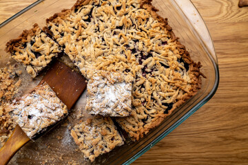 Sliced homemade grated berry pie, in a glass baking dish on a wooden board. Homemade cakes.