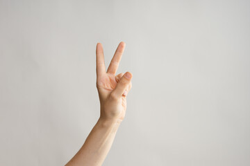 Hand gestures, Two thumbs up, a victory gesture. Women's hand . light grey background