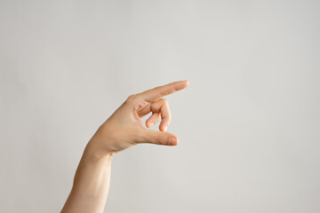 Hand gestures, Poke your finger, point to the side. Women's hand . light grey background