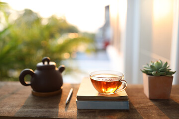 asian clay teapot and transparent cup with succulent plant and books on old wooden table relax home outdoor workspace