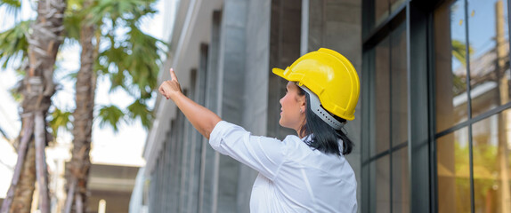 Female designer Pointing to the top left And wears a yellow helmet.