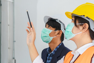 Builder young asian contractor team wear mask while inspecting the reconstructed construction, renovated or defect, check the finish before handing it over to the client at job site. Worker concept..