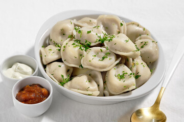 Boiled or steamed pelmeni in white bowl. Pelmeni are homemade pasta with mince meet filling wrapped...