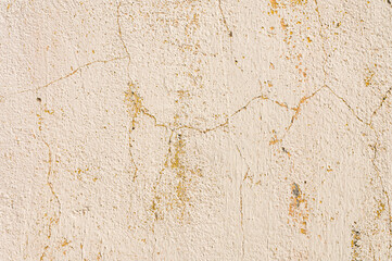 Grunge background of cracked peeling walls with peeled putty in beige tones.