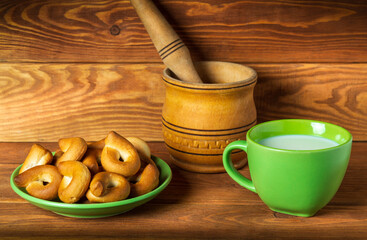 Milk mug and green plate with homemade bagels on vintage boards. Idea for a delicious festive breakfast or dinner