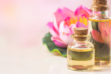bottle of aroma essential oil with candle and pink lotus on stone table, spa concept.
