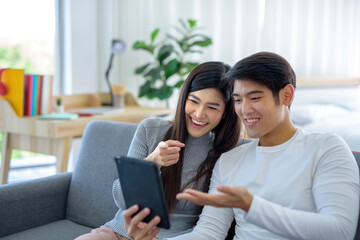 Go smiling Asian woman and play tablet on the sofa in the living room..