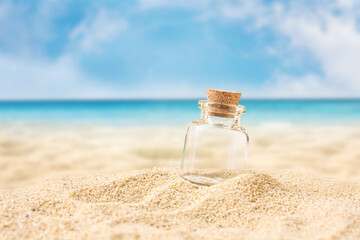 bottle on sand beach over blurred tropical blue sea and clear blue sky.