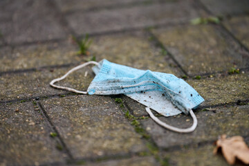 Used medical mask on street ground