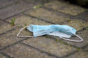 Used medical mask on street ground