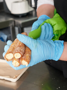 Hands Of A Chef Filling Some Cannoli With Cream