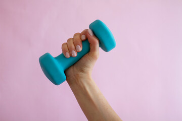 female hand holding dumbbell on pink background sport and healthy lifestyle concept