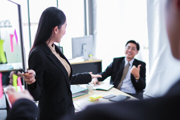 asia business man and woman pointing to paper post it on glass board explain document with manager in the office.businesswoman in meeting with colleagues, gesturing.Selective Focus
