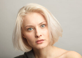 blond hair woman irritated and anoinng isolated on gray background close-up portrait