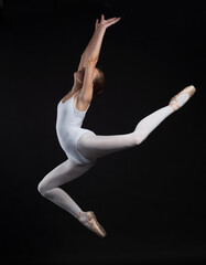 young gymnastic woman jumping in white body isolated on black background © Sergey Chumakov