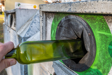 Grüne Flasche wird in den Altglascontainer geworfen