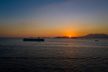 Fototapeta na wymiar Cargo ship pass out Victoria Harbour at sunset