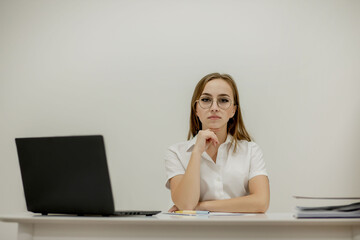 Close-up portrait of a young confident female office manager at her workplace, ready for doing business task.