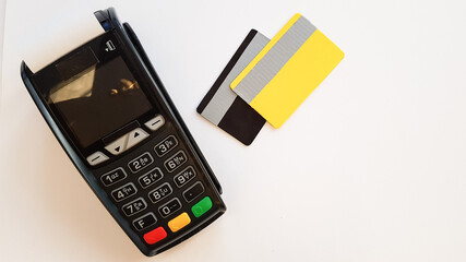 payment terminal for bank cards with bank cards on a white background. next to it there are 2 bank cards of gray and yellow color