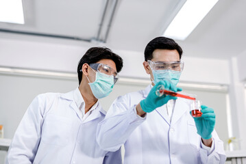 2 scientists Holding chemicals and looking at the camera.