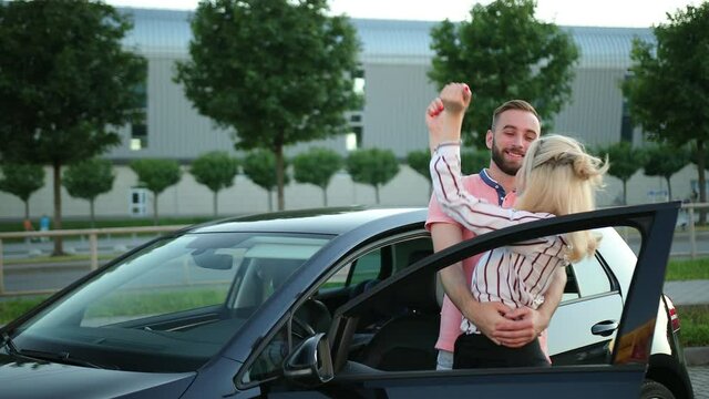 Young couple rejoices at the car, raises his hands up. Travel, honeymoon abroad