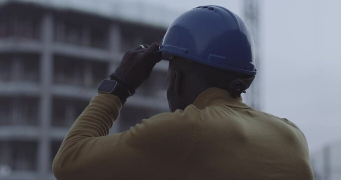 Slow motion close up of male an engineer putting a construction helmet on at dawn, ready for work