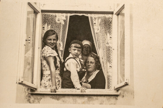 Latvia - CIRCA 1930s: A family sitting together in a window sill group shot. Children lived in a three generation family household. Vintage art deco era photo