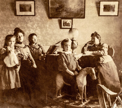 Russia - CIRCA 1900s: Group portrait shot of tree female and two children in dinning room. Boy playing on wooden rocking horse. Vintage Carte de Viste Victorian Edwardian era photo