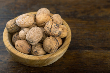 Walnut in wooden bowl on black background with copy space.