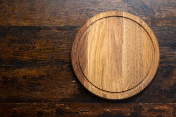 Empty round cutting board on a wooden table. Space for text.
