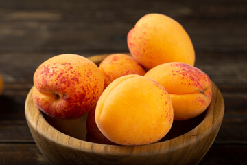 Fresh apricots in a wooden plate.