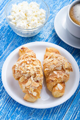 Morning breakfast. Fresh French croissant with coffee and cottage cheese on a blue wooden surface.