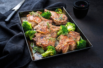Traditional barbecue dry aged veal chops with baby broccoli served as close-up in a rustic tray on...