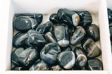 Black polished agate in wooden white boxes. Top view. Copy, empty space for text