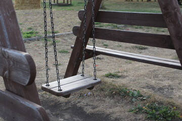 Fototapeta na wymiar close-up of an empty wooden swing in the playground 