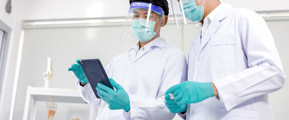 Two scientists were wearing a virus mask and were using technology to record or view information..