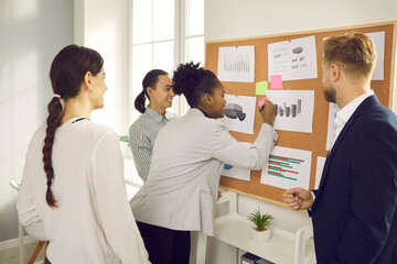 Fototapeta premium Group of positive international business partnes sharing opinions and adding information to marketing data statistics together. International teamwork, cooperation in business, brainstorm concept