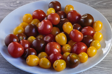 Multicolored tomatoes of different varieties in a dish. Fashionable vegan food.