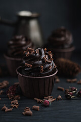 Muffin or cupcake with chocolate shaped cream at black table. Flatlay top view